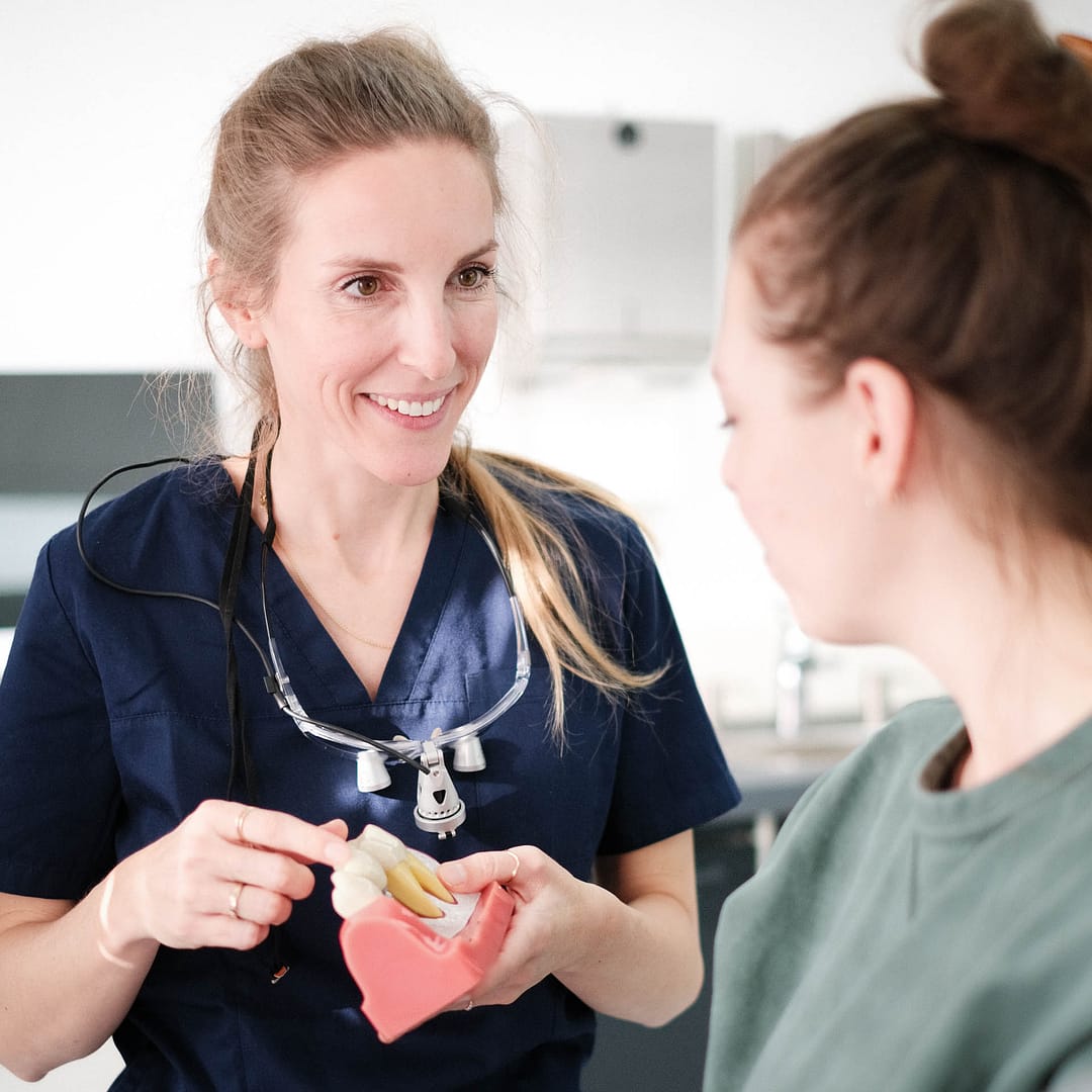 DSCF5754_square Friederike Kutscher redet mit einer Patientin. Sie hält dabei ein Zahnmodell in der Hand.